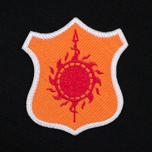 May include: Orange and white embroidered patch with a red sun and a spear in the center.