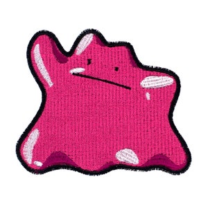 以下が含まれることがあります： 顔のある水滴のようなキャラクターが描かれたピンクと白の刺繍パッチ。