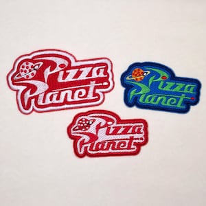May include: Three embroidered patches featuring the text Pizza Planet in a stylized font. Two patches are red with white lettering and a red planet icon, while one patch is blue with green lettering and an orange planet icon with a ring.