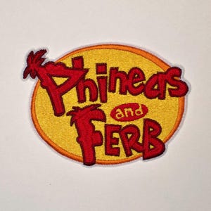 May include: An oval-shaped embroidered patch featuring a yellow background with a thick orange border. The text Phineas and Ferb is stitched in red with a stylized font, with the word and appearing in a smaller red oval in the center.