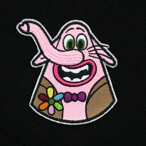 May include: Embroidered patch featuring a pink cartoon character with a long trunk, large smile, and green eyes. The character wears a brown jacket, a purple bow tie, and a colorful flower. The patch has a white border and is set against a black background.