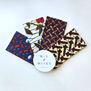 May include: An overhead shot of five fabric swatches with colorful patterns. The swatches are arranged around a white circular sticker that reads "WAX & WOVEN". The fabrics feature designs in red, blue, and yellow.