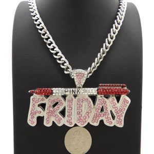 May include: Silver chain necklace with a large pendant that says "PINK FRIDAY" in pink and red rhinestones. The pendant is shaped like a lipstick tube.
