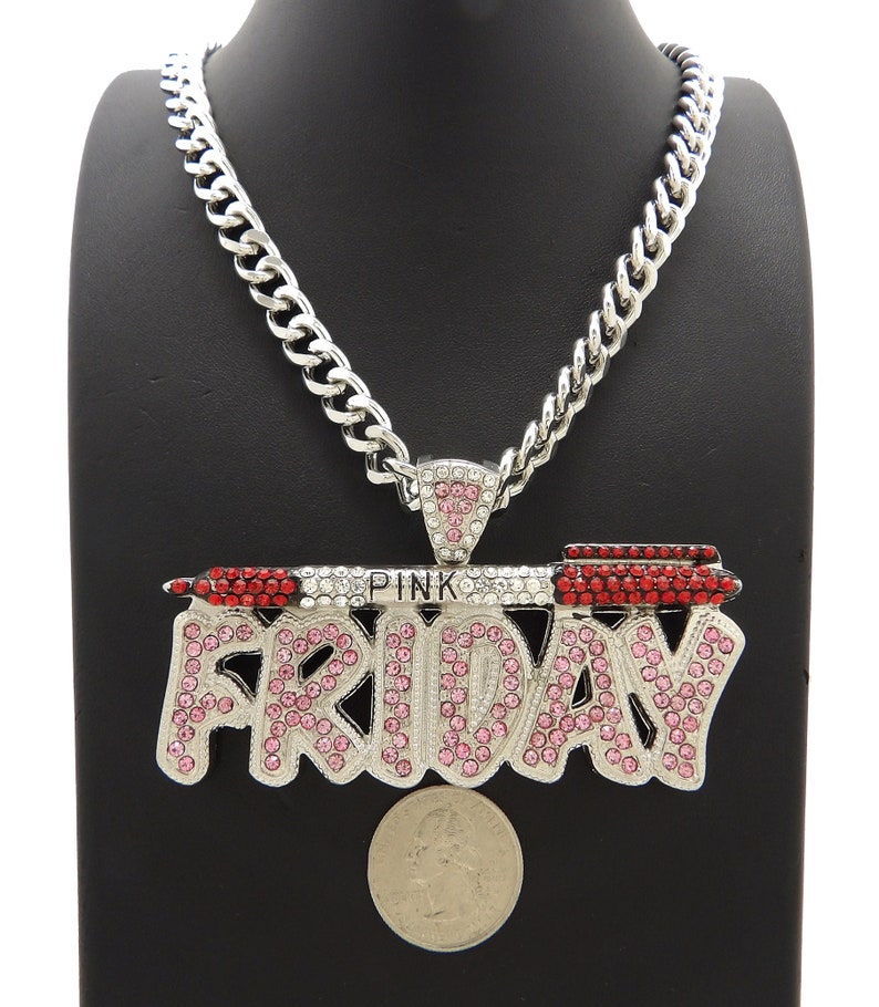 May include: Silver chain necklace with a large pendant that says "PINK FRIDAY" in pink and red rhinestones. The pendant is shaped like a lipstick tube.