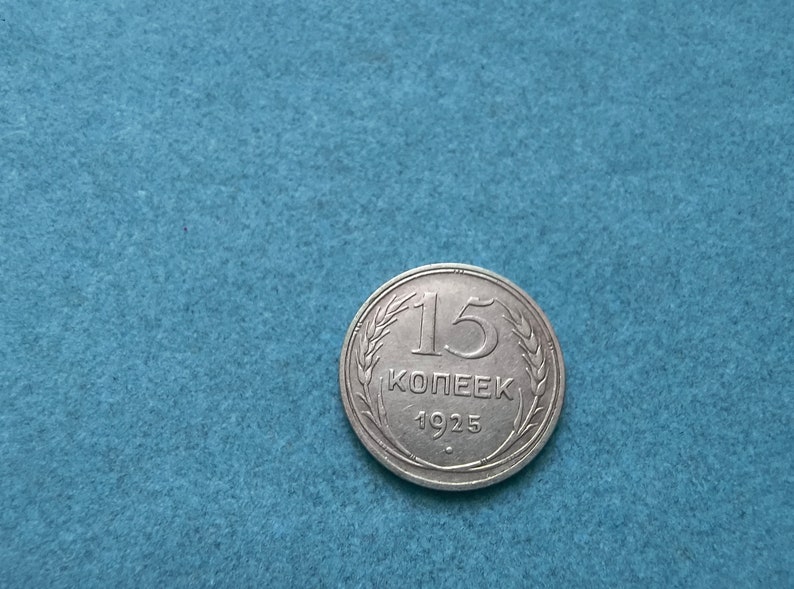May include: A silver 15 kopeek coin from 1925, featuring a wheat wreath design and the year 1925.