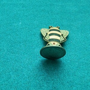 May include: A gold-colored bee figurine standing on a 1974 Soviet 5 kopecks coin. The bee has black stripes and a red stinger.