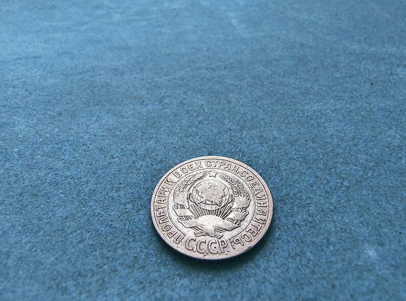 May include: A silver coin with the text "ПРОЛЕТАРИИ ВСЕХ СТРАН, СОЕДИНЯЙТЕСЬ!" and the text "СССР 1959" around a globe with a star on top.