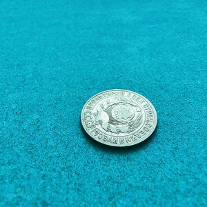 May include: A silver coin with the text "ПРОЛЕТАРИАТ ВСЕХ СТРАН, СОЕДИНЯЙТЕСЬ!" around the edge and a stylized image of a globe with wheat stalks in the center.