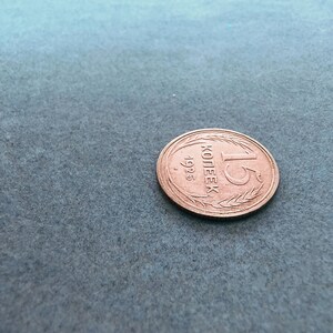 May include: A copper-colored coin with the inscription "1 копейка 1925" (1 kopeck 1925) in Cyrillic script.