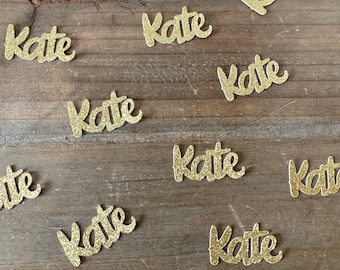 May include: Gold glitter confetti with the name "Kate" written on each piece.
