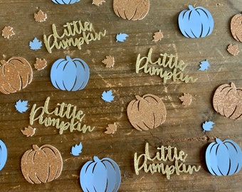 Op de afbeelding: Een verzameling herfstthema papieren uitsparingen, waaronder goudglitter pompoenen, lichtblauwe pompoenen en goudglitter bladeren. De woorden "little pumpkin" zijn geschreven in goudglitter schrift. Geplaatst op een houten oppervlak.