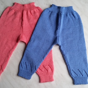 Puede incluir: Dos pares de pantalones de punto para bebé, uno en rosa y otro en azul. Los pantalones tienen un diseño sencillo y están hechos con un hilo suave y cómodo.
