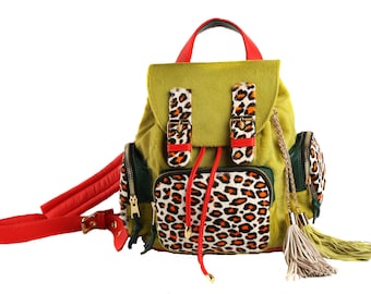 May include: A green, red, and brown backpack with a leopard print design. The backpack has a drawstring closure and two adjustable straps.