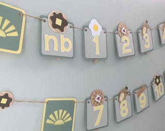 Fotos mensuales del primer cumpleaños, pancarta con temática de desayuno, decoraciones para fiestas, combinación de colores verde salvia y amarillo.