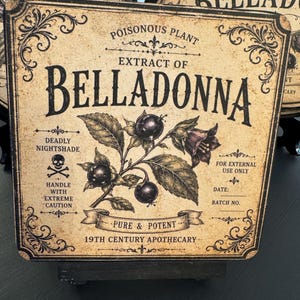 May include: A square sign with a beige, aged background featuring black text and a botanical illustration of a belladonna plant. The text reads: Poisonous Plant, Extract of Belladonna, Deadly Nightshade, Handle with Extreme Caution, For External Use Only, Pure & Potent, 19th Century Apothecary, Date, and Batch No.
