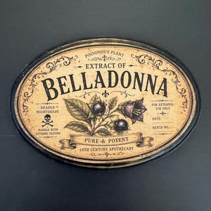 May include: An oval-shaped sign with a distressed beige background and black border. The text reads: POISONOUS PLANT EXTRACT OF BELLADONNA, DEADLY NIGHTSHADE, FOR EXTERNAL USE ONLY, PURE & POTENT, 19TH CENTURY APOTHECARY. It features a skull icon and botanical illustrations.