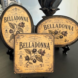 May include: Three decorative signs featuring vintage-style labels for Belladonna extract. Two signs are oval and one is square, all displaying botanical illustrations of nightshade, skull and crossbones icons, and text reading Poisonous Plant.