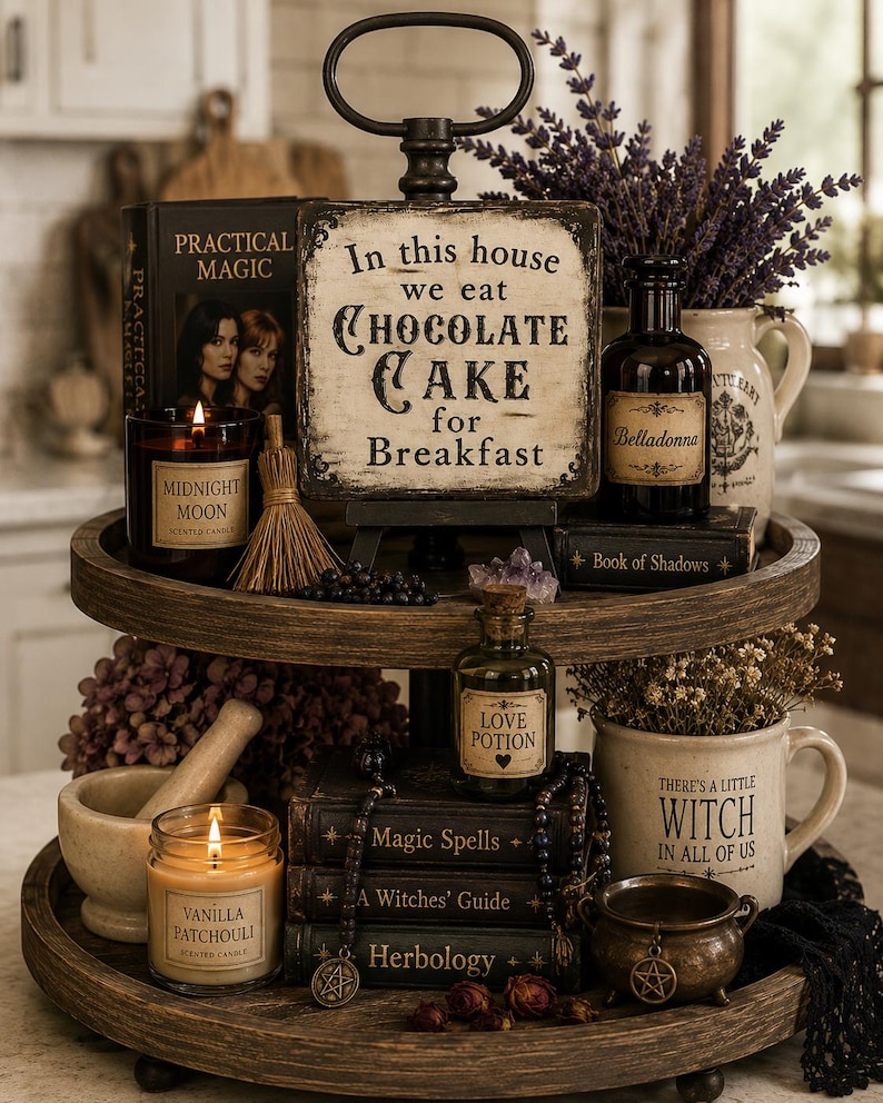 May include: A two-tiered wooden tray display featuring a sign that reads In this house we eat CHOCOLATE CAKE for Breakfast, alongside a Midnight Moon candle, a Belladonna bottle, a Book of Shadows, a Love Potion bottle, and a Vanilla Patchouli candle.