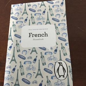 May include: A "French Phrasebook" with a white cover and a pattern of blue Eiffel Towers, bicycles, wine bottles, and croissants. The Penguin logo is on the bottom right.