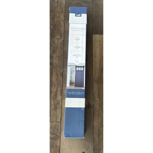 May include: A blue rectangular box for a barn door hardware kit. The box has white text that reads "BARN DOOR hardware kit". The box also shows an image of a blue barn door. The box is on a wooden surface.