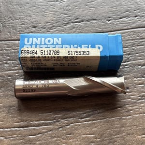 May include: A silver-colored metal end mill cutter with the text U.B. 7/8 HS USA LEAD 4.760 0229P engraved on the side, positioned below a blue plastic storage case labeled UNION BUTTERFIELD with a white sticker showing 698464 5110709 S1755353.