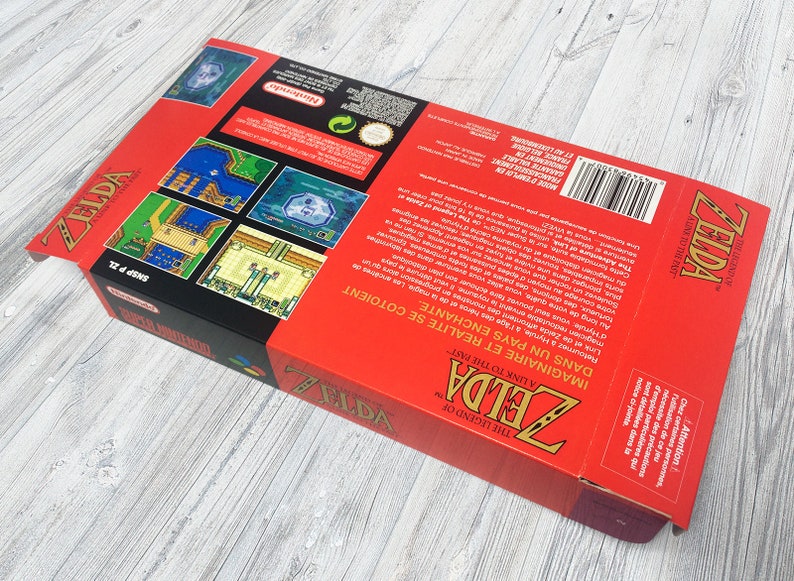 May include: A red and black Super Nintendo game box for The Legend of Zelda: A Link to the Past. The box features a picture of Link and the text "In an enchanted land. Imagine a land where reality and fantasy meet."