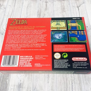 May include: Red and black video game box for The Legend of Zelda: A Link to the Past for the Super Nintendo Entertainment System. The box features a barcode, game screenshots, and text in French.