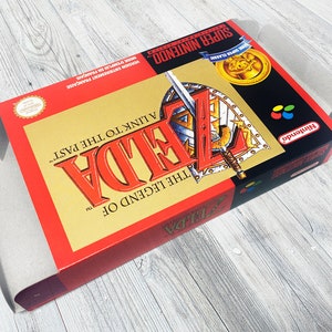 May include: A red and gold Super Nintendo game cartridge for The Legend of Zelda: A Link to the Past. The game cartridge has a picture of Link holding a sword and shield.