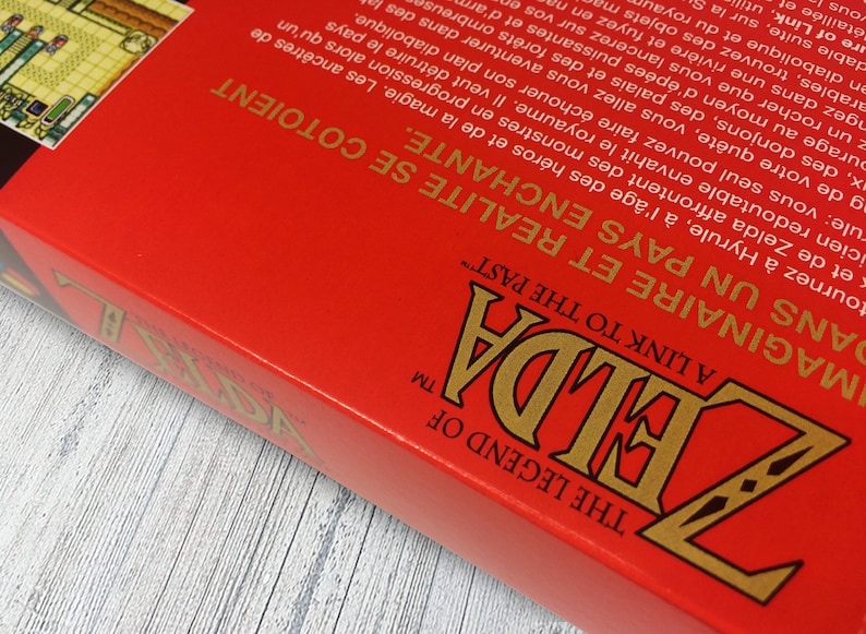 May include: A red box with the words "The Legend of Zelda" and "A Link to the Past" in gold lettering. The box is for a video game.