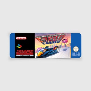 May include: A blue Super Nintendo Entertainment System game cartridge with a red, white, and blue F-Zero logo. The game is made in Japan and features a futuristic racing theme.