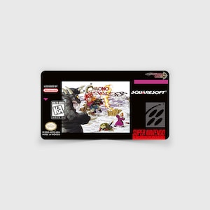 May include: A black Super Nintendo game cartridge with a colorful image of a character fighting a monster. The game title is "Chrono Trigger" and the game developer is "Squaresoft".