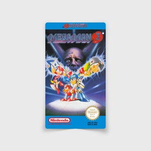 Könnte beinhalten: Eine blaue Nintendo Entertainment System-Spielkassette für Mega Man 3. Die Vorderseite der Kassette zeigt eine farbenfrohe Illustration von Mega Man und mehreren Robotermeistern. Der Text "MEGA MAN 3" ist in Weiß auf schwarzem Hintergrund gedruckt. Das Nintendo-Gütesiegel ist in der rechten unteren Ecke sichtbar.