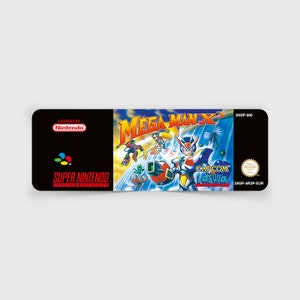 Könnte beinhalten: Super Nintendo Entertainment System-Spielkassette für Mega Man X3, mit einem blauen und roten Robotercharakter mit einer großen Waffe, vor einem blauen und weißen Hintergrund. Der Text "Mega Man X3" ist in großen weißen Buchstaben. Der Text "CAPCOM Laguna" ist in weißen Buchstaben auf schwarzem Hintergrund. Der Text "SNSP-006" ist in weißen Buchstaben auf schwarzem Hintergrund.