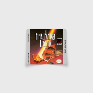 Peut inclure: Une cartouche de jeu Game Boy vintage pour The Final Fantasy Legend, avec un fond rouge et orange et un personnage portant un casque. Le texte "ORIGINAL GAME BOY" est visible dans le coin supérieur droit. Le texte "THIS SIDE OUT" est visible sur le côté droit de la cartouche.
