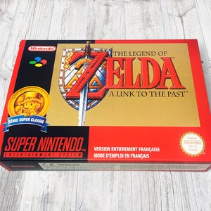 May include: A red and gold Super Nintendo Entertainment System game box for The Legend of Zelda: A Link to the Past. The box features a gold coin with a cartoon character wearing a green hat and a red shirt. The box also features a gold seal with the words "Original Nintendo Seal of Quality".