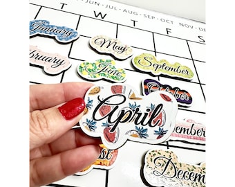 Puede incluir: Un conjunto de doce azulejos magnéticos de calendario mensual coloridos con fondo blanco. Cada azulejo presenta un mes diferente del año con un diseño único. El mes de abril se destaca y presenta un diseño de sandía y piña.