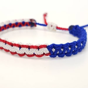 May include: A red, white, and blue braided friendship bracelet with a sliding knot closure.