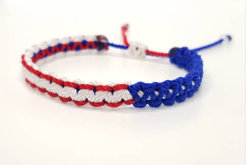 May include: A red, white, and blue braided friendship bracelet with a sliding knot closure.