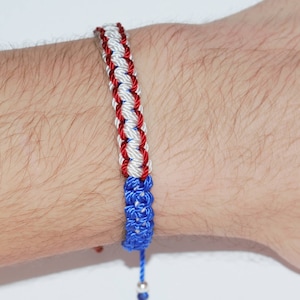 May include: A red, white, and blue braided bracelet with a silver bead at the end.