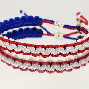May include: A red, white, and blue friendship bracelet made of braided string.