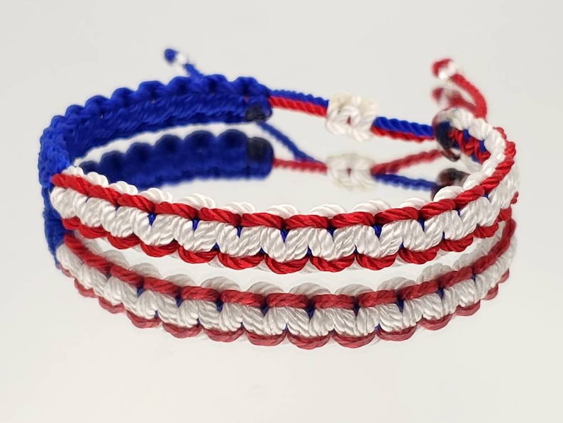 May include: A red, white, and blue friendship bracelet made of braided string.