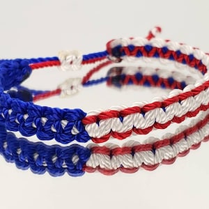 May include: A red, white, and blue friendship bracelet made with braided string.