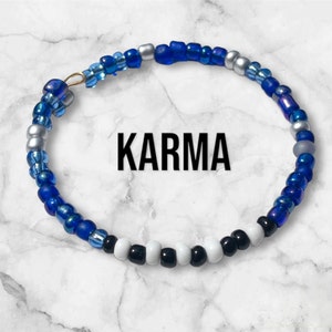 May include: A blue, white, and silver beaded bracelet with the word "KARMA" in black lettering.