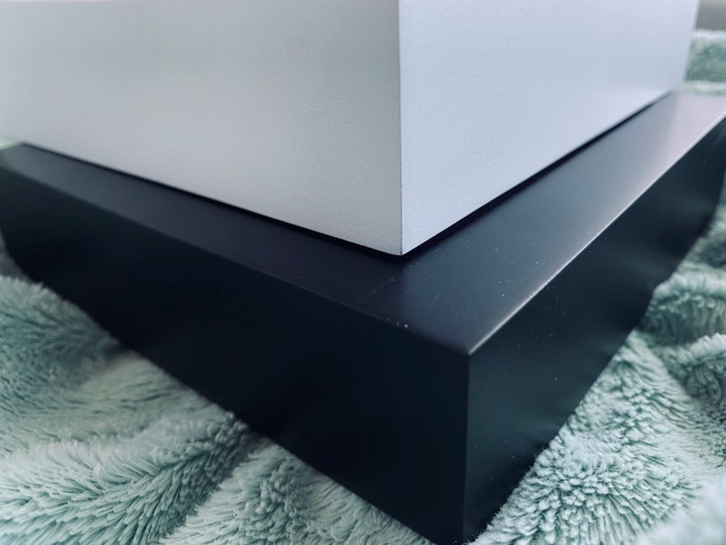 May include: A white box sits on top of a black box. Both boxes are made of wood and have a smooth, polished finish.
