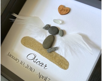 Peut inclure: Un mémorial encadré avec un fond blanc, un petit cœur en bois avec le mot "Love" inscrit dessus, une petite coquille blanche, un petit tas de sable, un ange de pierre fait de pierres grises et le texte "Oscar January 10, 2010 - April 7, 2024".
