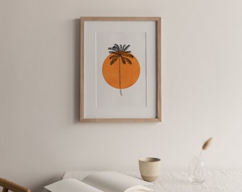 May include: A framed print of a black palm tree silhouette against a large orange circle. The print is in a light wood frame and is hanging on a white wall.
