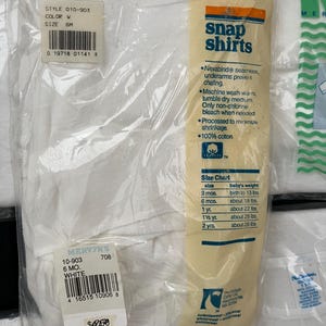 Puede incluir: Un paquete blanco de dos camisas con botones a presi&oacute;n para beb&eacute;s. El paquete incluye una tabla de tallas con edades y pesos. El paquete tambi&eacute;n tiene el texto "Snap Shirts" y "100% algod&oacute;n".