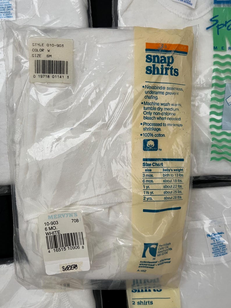 Puede incluir: Un paquete blanco de dos camisas con botones a presi&oacute;n para beb&eacute;s. El paquete incluye una tabla de tallas con edades y pesos. El paquete tambi&eacute;n tiene el texto "Snap Shirts" y "100% algod&oacute;n".