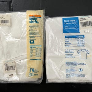 Puede incluir: Dos paquetes de camisetas blancas para beb&eacute;s. El paquete de la izquierda est&aacute; etiquetado como "Snap Shirts" y tiene una tabla de tallas. El paquete de la derecha est&aacute; etiquetado como "Sprockets 2 Slip-on Shirts" y tiene una tabla de tallas con rangos de peso para reci&eacute;n nacido, peque&ntilde;o, mediano y grande.