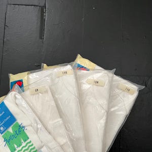 Puede incluir: Un paquete de cinco camisetas blancas para beb&eacute;s en diferentes tallas. Las tallas est&aacute;n etiquetadas como 6M, 1YR, 18M y 2YR. Las camisetas est&aacute;n hechas de 100% algod&oacute;n peinado.